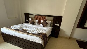 A bedroom with a large bed, a wooden headboard, and a tiled floor. - Velora Inn  (Varanasi)