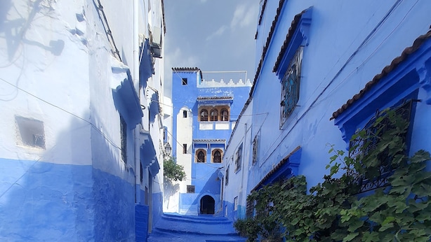 A narrow alleyway with cobblestone pavement leading to a building with blue and white walls. - hostel aline (Chefchaouen)