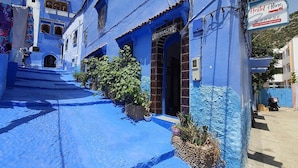 A building with a blue exterior, a sign for 'Hostel Aline', and a staircase leading to the entrance. - hostel aline (Chefchaouen)