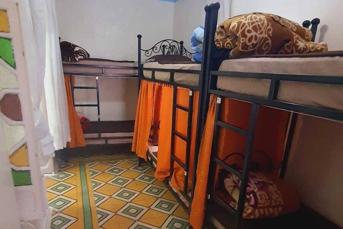 Ein Schlafsaalzimmer mit Etagenbetten, einem gemusterten Boden und einer Deckenleuchte.
