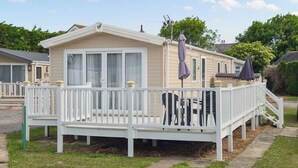 A mobile home with a deck, outdoor seating, and a covered patio area. - 3 bedroom accommodation in Hayling Island (Hayling Island)