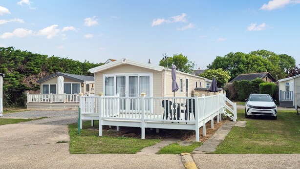 A single-story mobile home with a porch and a car parked in front. - 3 bedroom accommodation in Hayling Island (Hayling Island)