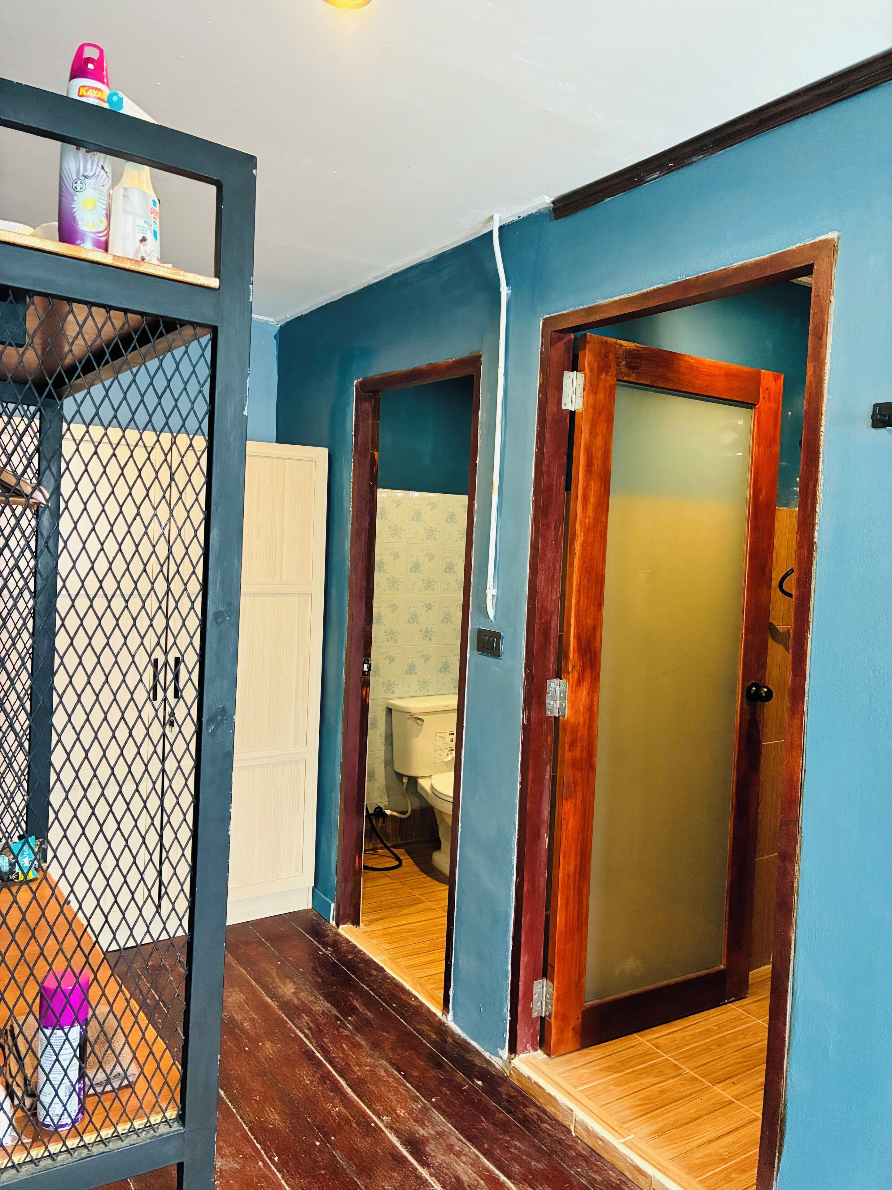 A room with a wooden floor, a blue wall, and a wooden door with a frosted glass panel.