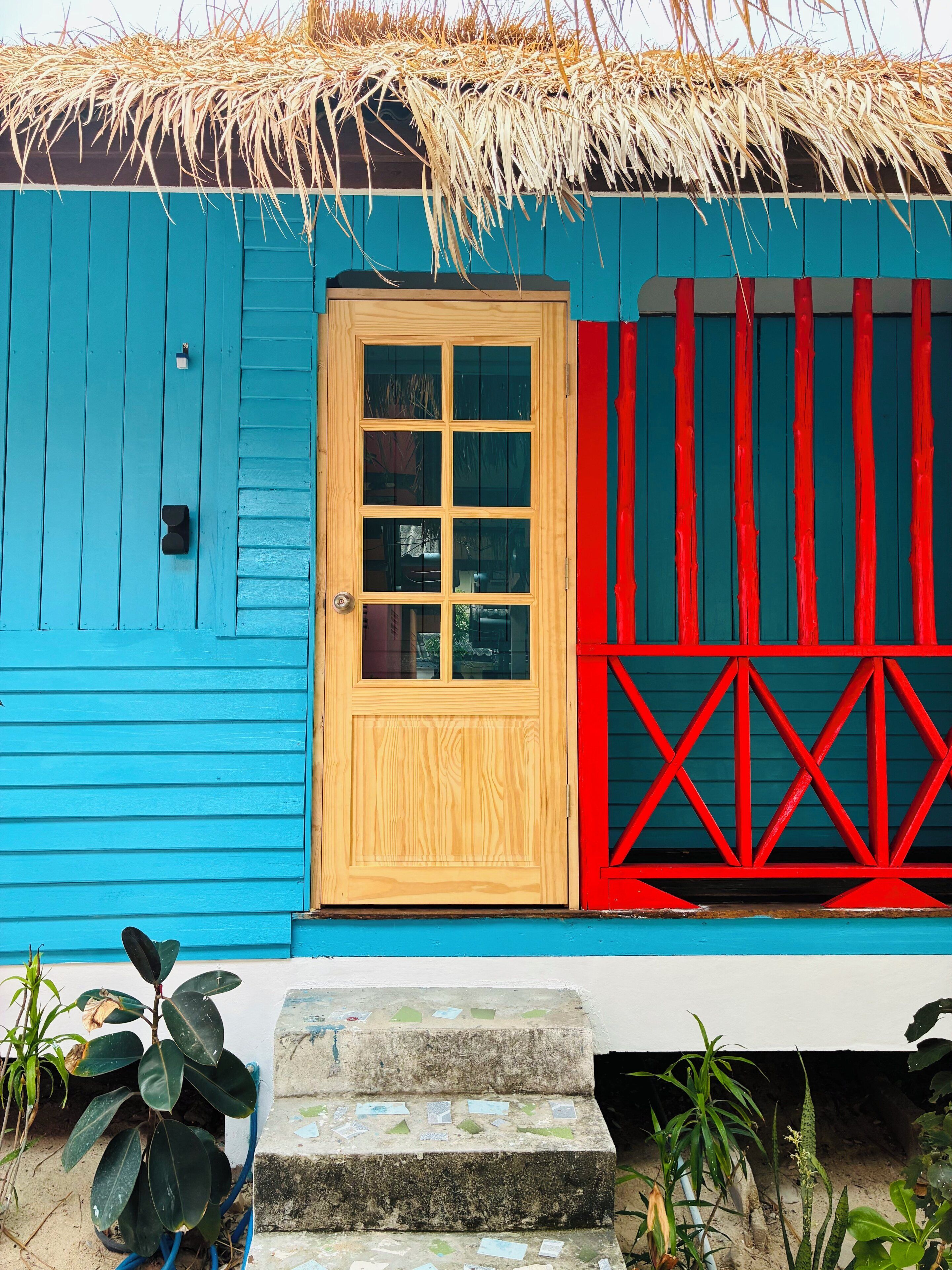 A house with a blue exterior, a wooden door, and a red fence.