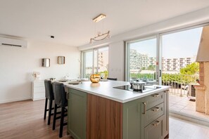 Une cuisine moderne dotée d’un grand îlot central, de tabourets de bar, d’une vue sur la ville et d’un balcon avec une rambarde.