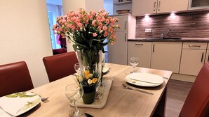 Une table à manger dressée avec des assiettes, des couverts et un vase de fleurs.