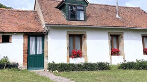 A two-story house with a red-tiled roof, a green door, and a chimney. - Charming cottage in Lurcy-Lévis with air conditioning and garden (Lurcy-Lévis)