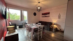 Un coin repas accueillant avec une table mise pour deux, un canapé et une lampe.