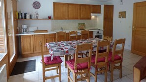 A compact kitchen with wooden cabinets, a dining table with chairs, and a clock on the wall. - Spacious 4-room apartment for 6-8 people with terrace in Grand-Bornand (Le Grand-Bornand)