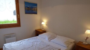 A bedroom with a bed, two bedside tables, a window, and a wall-mounted picture. - Spacious 4-room apartment for 6-8 people with terrace in Grand-Bornand (Le Grand-Bornand)