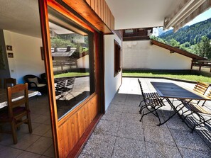 A patio with outdoor furniture, a wooden door, and a view of a mountainous landscape.