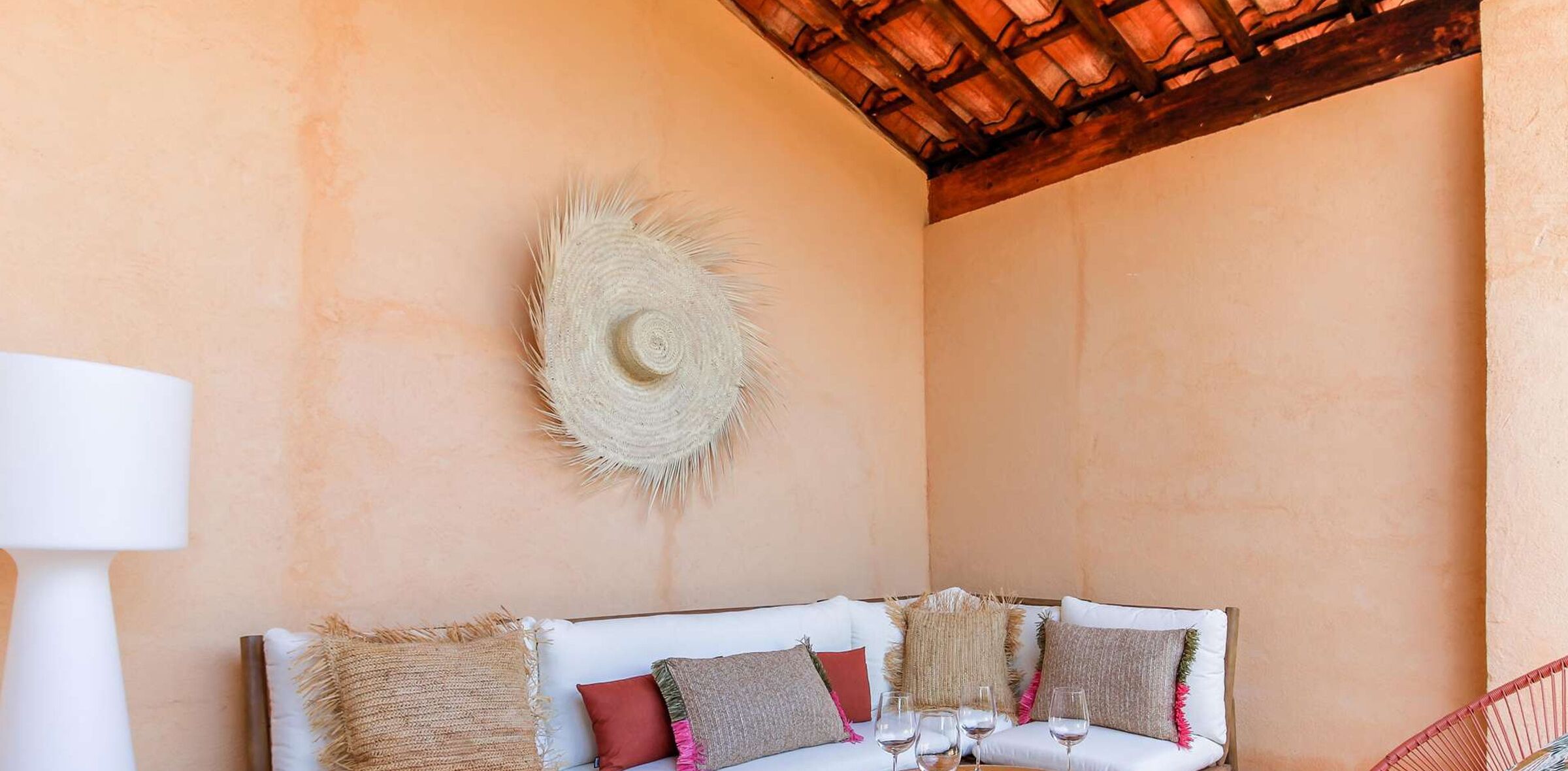 Una habitación acogedora con un sofá blanco, un adorno de pared tejido y una mesa con vasos.
