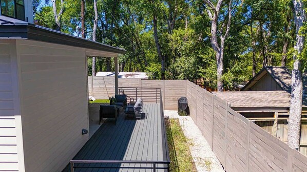 A wooden deck with outdoor seating, a covered area, and a fenced yard.