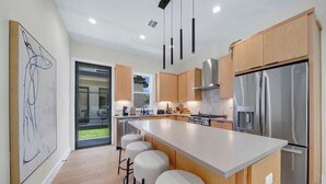 A modern kitchen with a large island, stainless steel appliances, and wooden cabinets.