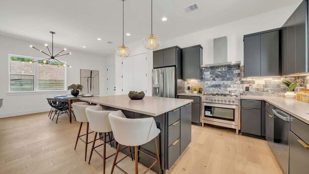 A modern kitchen with a central island, bar stools, and stainless steel appliances. - Great Deal, 6bd, Pool,  Game Room & Chef Kitchen (Austin)