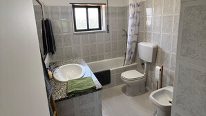 A bathroom with a sink, toilet, bathtub, and shower curtain.