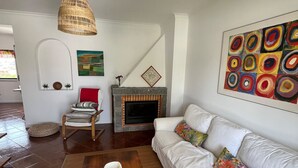 A living room with a white sofa, a wooden coffee table, a fireplace, and a colorful abstract painting.