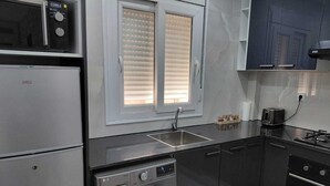 Eine kleine Küche mit Waschmaschine, Mikrowelle, Spüle und Toaster.
