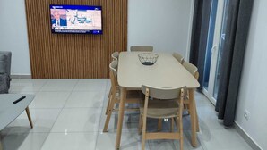 Ein moderner Essbereich mit einer Holzwand, einem Flachbildfernseher und einem Tisch mit Stühlen.