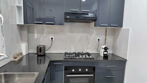 Eine moderne Küche mit dunklen Schränken, einem Gasherd, einem Backofen und einer Spüle aus Edelstahl.