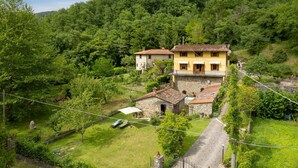 A hillside property with two yellow buildings, a stone structure, and a grassy area with a pathway.