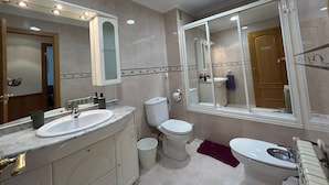 Un bagno moderno con uno specchio grande, un lavandino, un WC e un bidet.