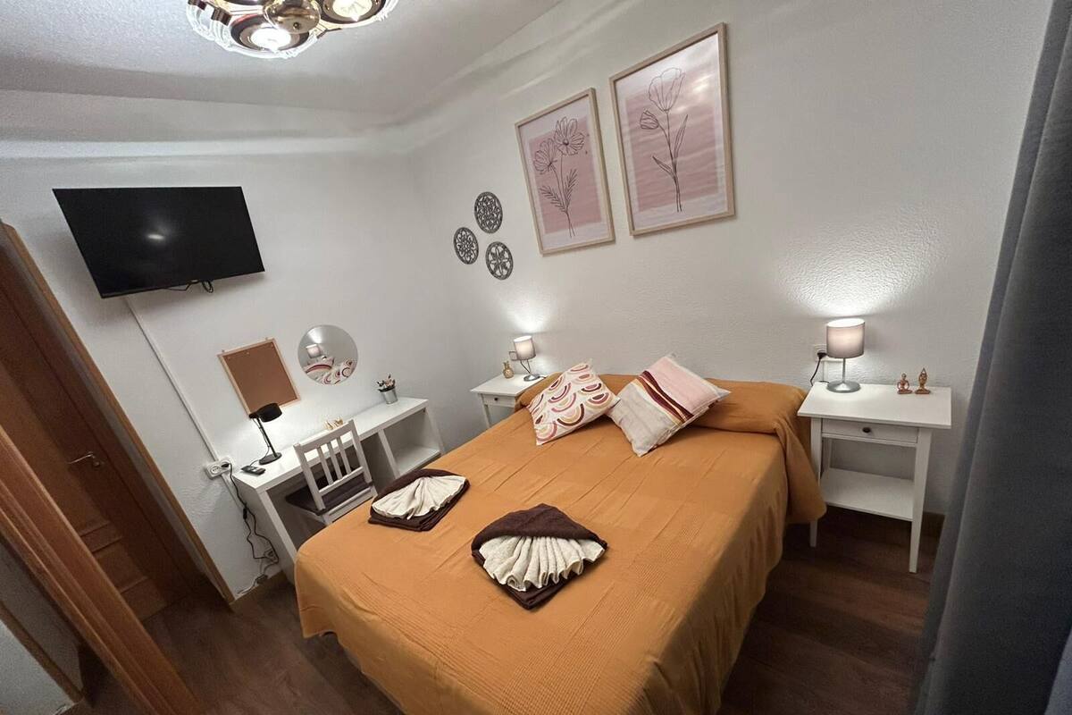 Habitación de hotel con cama, mesitas de noche, escritorio, silla, televisor y decoración mural.