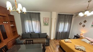 Una camera accogliente con un tavolo da pranzo in legno, una poltrona, un letto con copriletto giallo e un lampadario.