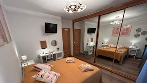 Una camera da letto con un letto grande, una scrivania, una sedia, una TV e uno specchio.