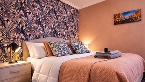 A neatly made bed with a patterned headboard, a bedside lamp, and a folded towel on the nightstand. - Apartment Mari&Lucio-Metro Basilica S.Paolo, 4 stops to Colosseum, 15min Termini (Roma)