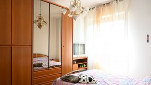 Ein Schlafzimmer mit Bett, Kleiderschrank, Fernseher und Spiegel.