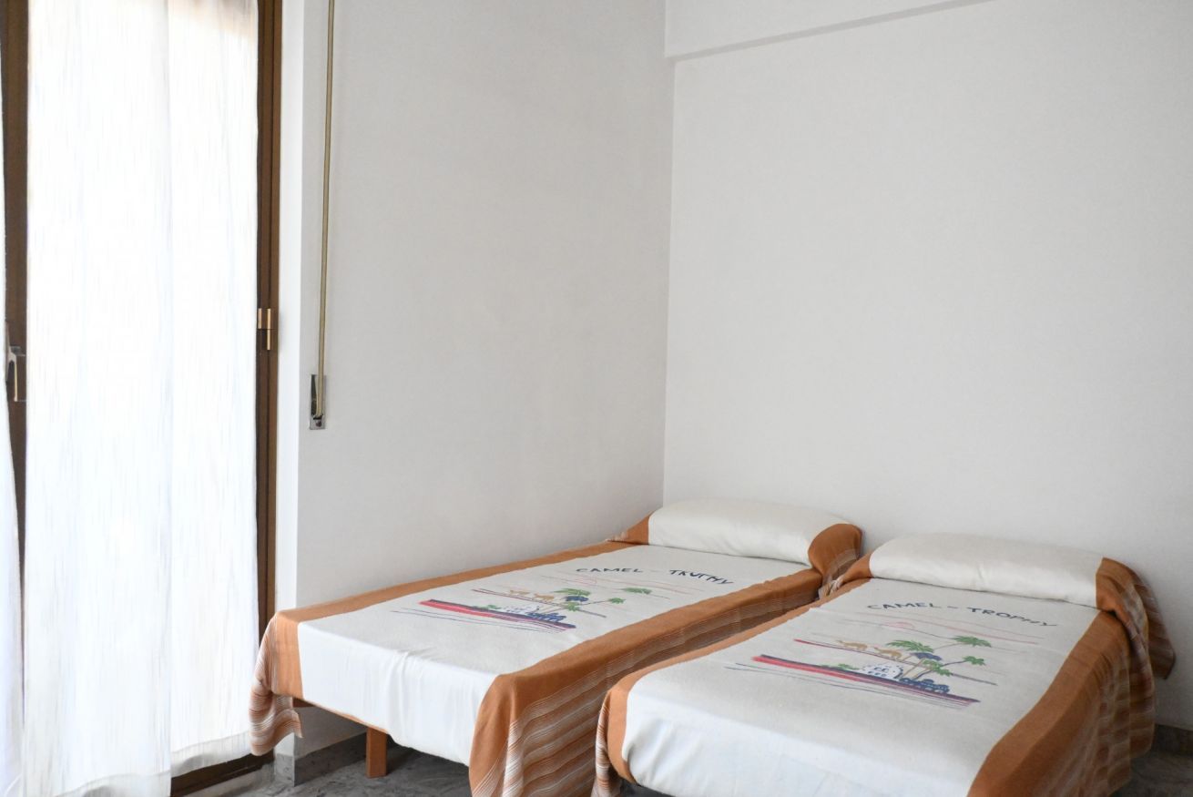 A room with two single beds, a wooden door, and a curtain.