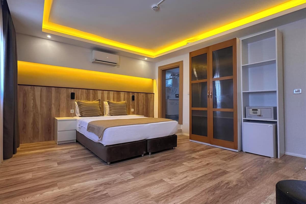 A modern bedroom with a wooden headboard, a bed with white bedding, a nightstand, and a wardrobe with a combination of open and closed doors.