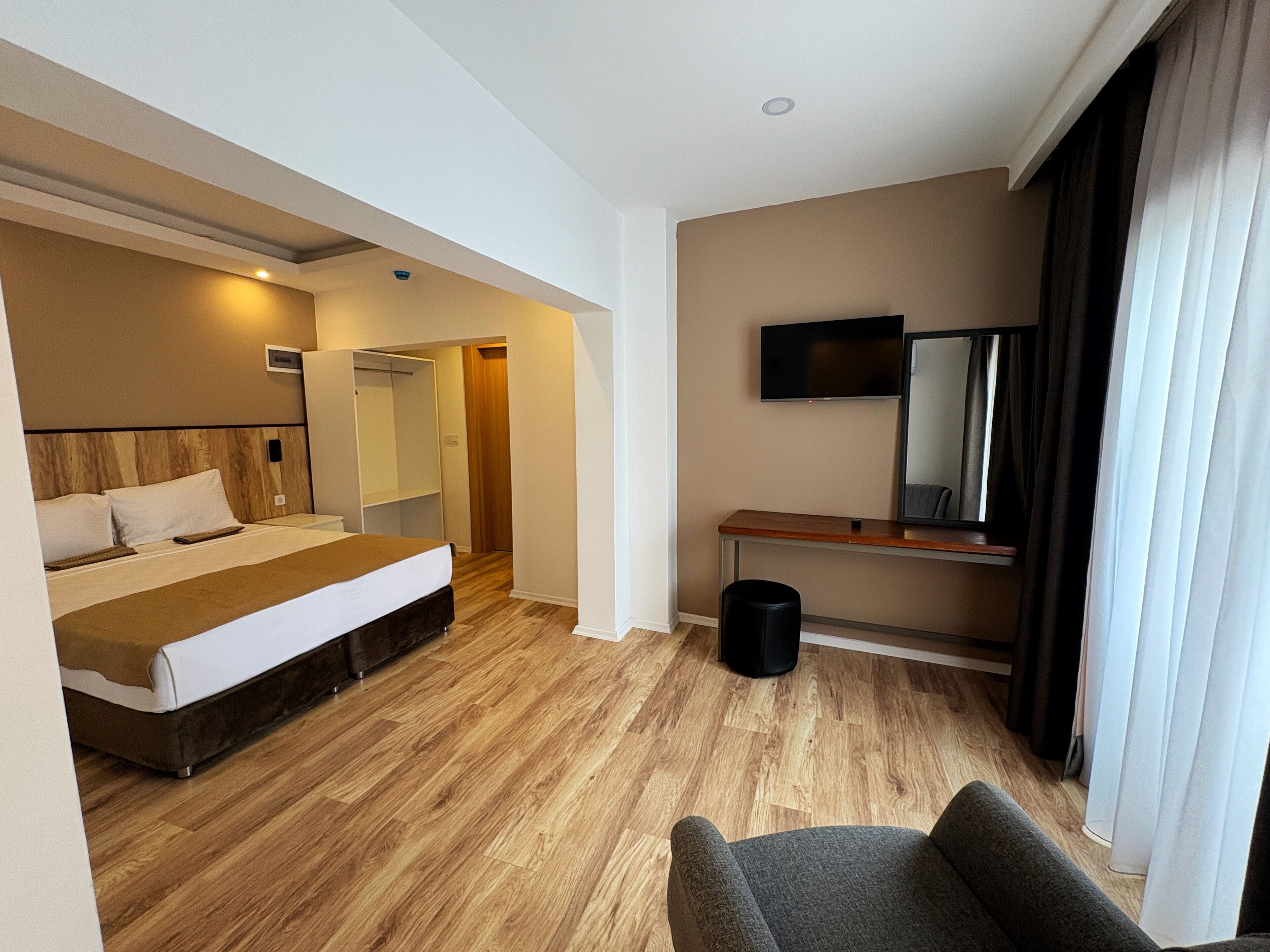A hotel room with a bed, a desk, a chair, a TV, and a mirror.
