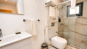 Un baño con ducha de mármol, inodoro, lavabo y espejo.