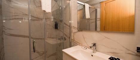 Une salle de bain moderne avec une douche à parois de verre, un lavabo blanc et un meuble en bois.