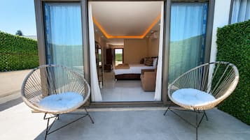 Ein modernes Interieur mit einem Bett, zwei Korbstühlen und einer Glastür, die auf einen Balkon führt.