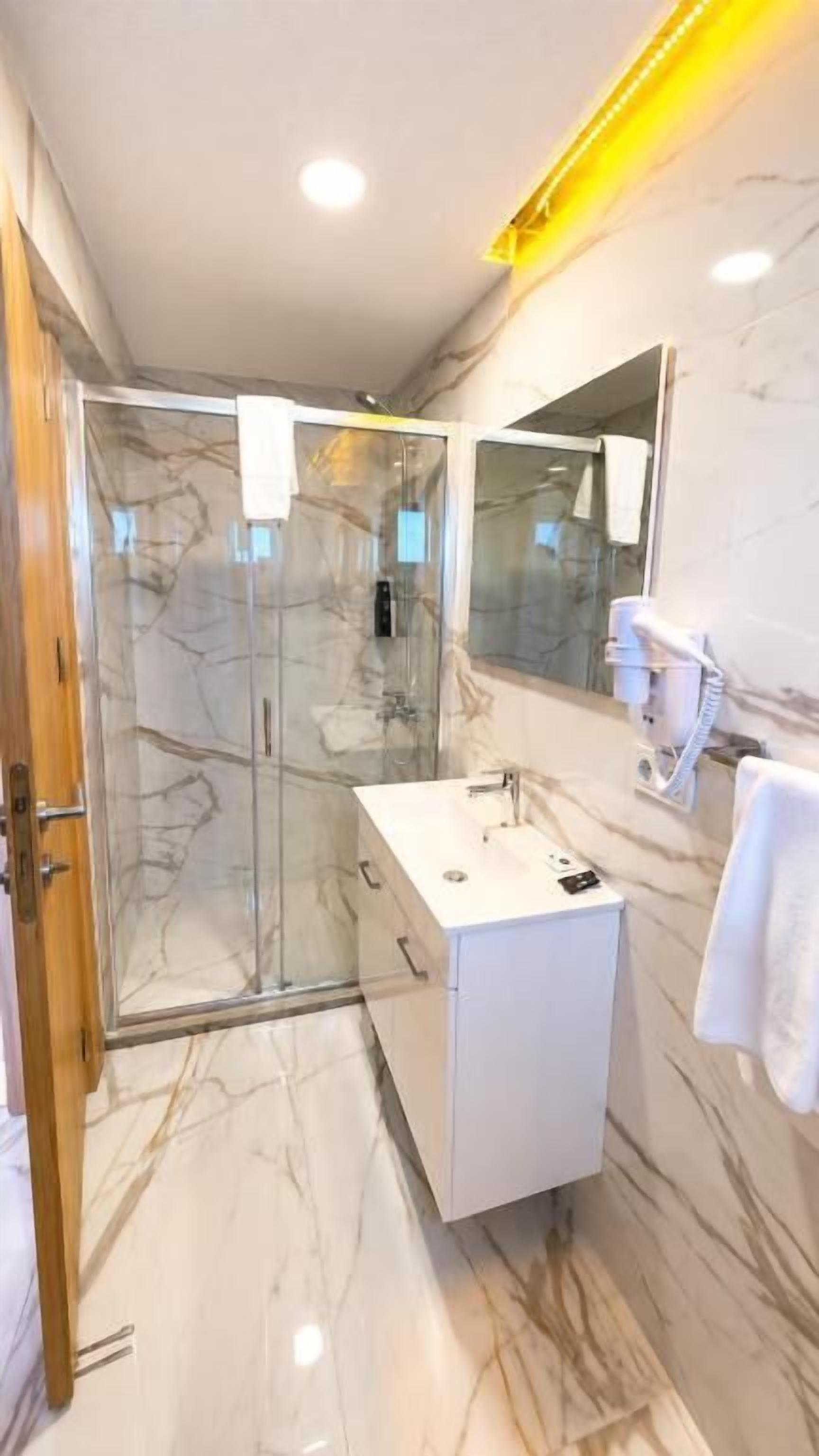 A modern bathroom with a glass shower enclosure, a white vanity, and a large mirror.