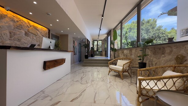 A reception area with a stone wall, a wooden reception desk, and wicker chairs.
