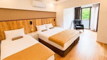 Ein Hotelzimmer mit zwei Betten, einem Holzkopfende, einem Stuhl und einem großen Fenster mit Vorhängen.