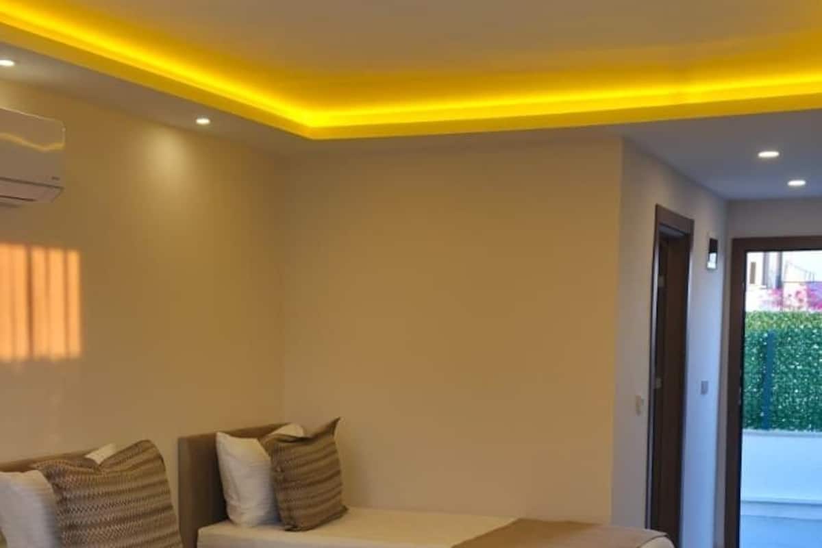 A modern hotel room with two beds, a wooden floor, and a view of the outside.