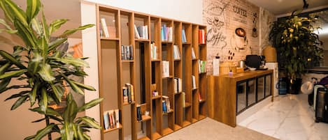 A modern interior with a wooden bookshelf filled with books, a coffee machine, and a large potted plant.