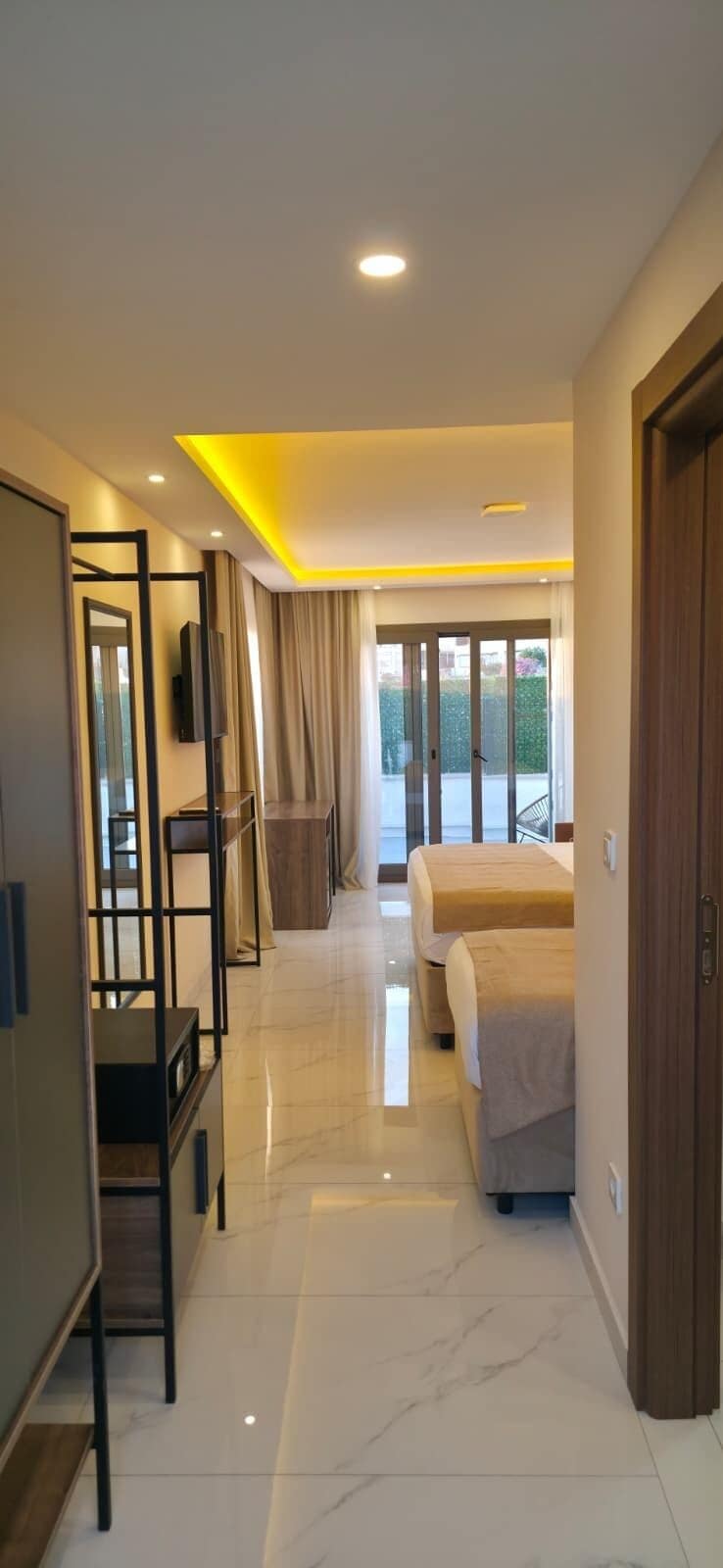 Quarto de hotel moderno com uma cama grande, televisão, guarda-roupa e varanda com vista.