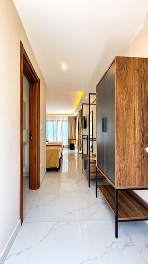 Un pasillo de hotel con un armario de madera, una cama y un televisor en la pared.