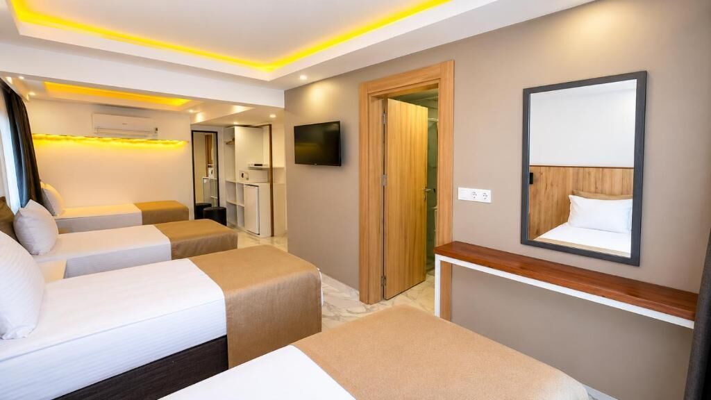 Een hotelkamer met twee bedden, een televisie, een spiegel en een houten deur.
