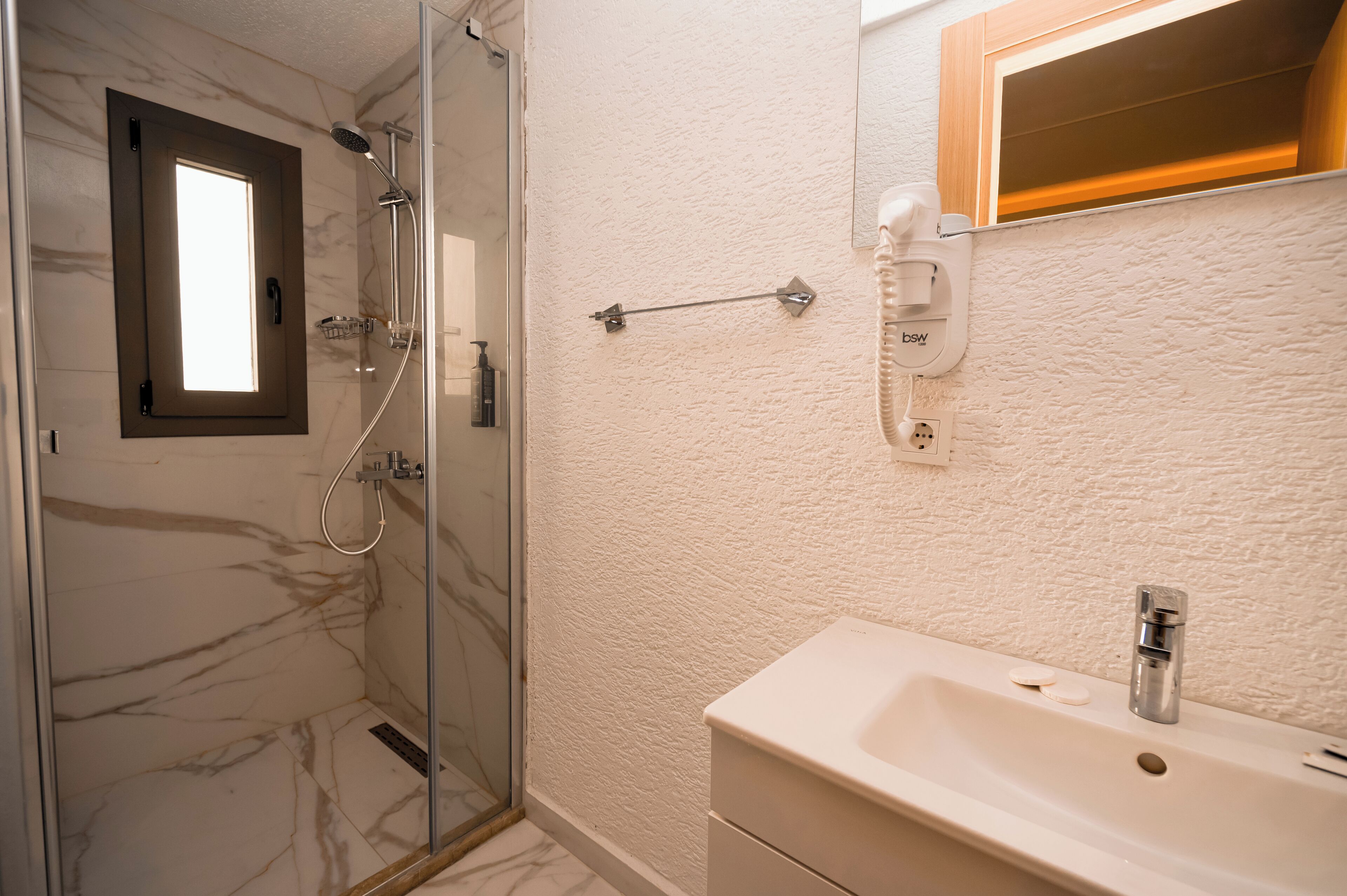 Une salle de bain avec une douche à parois de verre, un lavabo blanc et un miroir au-dessus.