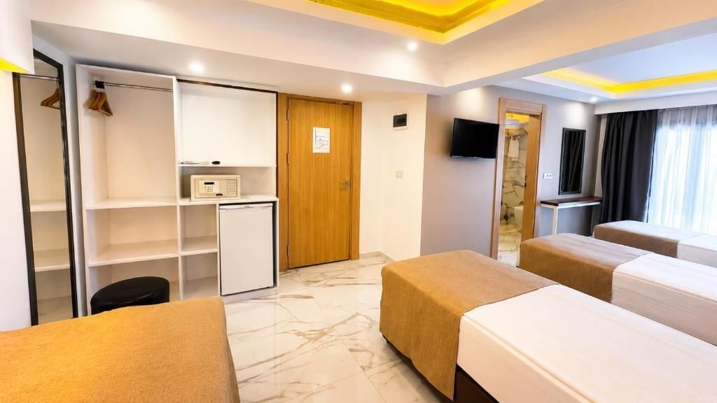 Una habitación de hotel con una cama, un escritorio, un armario y un televisor.