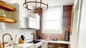 A modern kitchen with white cabinetry, a stainless steel sink, and a wooden floor. - Charming 1-bedroom condo that sleeps 4 in enchanting Savannah on Historic Square (Savannah)