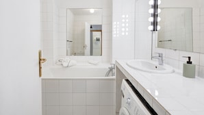 Une salle de bain moderne équipée d’une baignoire, d’un lavabo, d’un miroir avec éclairage intégré et de toilettes.