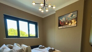 Quarto com uma cama grande, uma escrivaninha e uma janela.